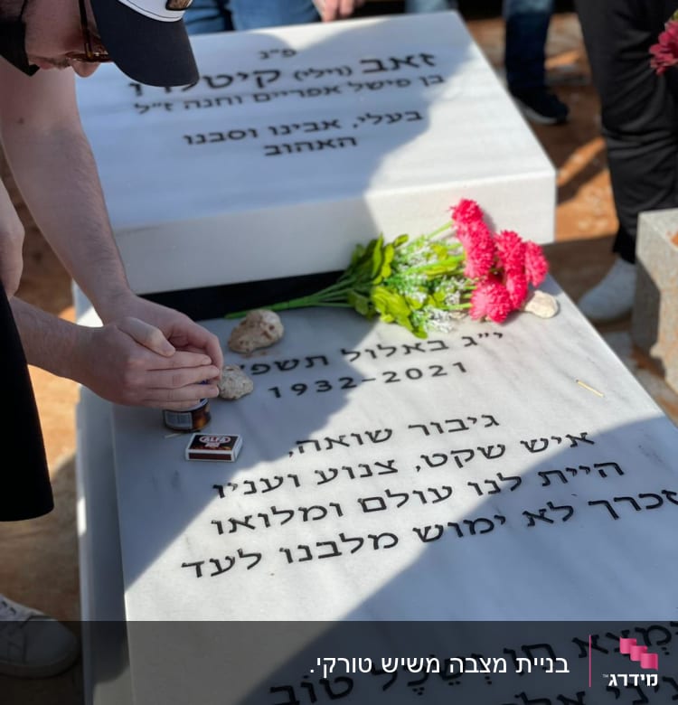 שני מצבות עם כיתוב בעברית ופרחים מונחים עליהן